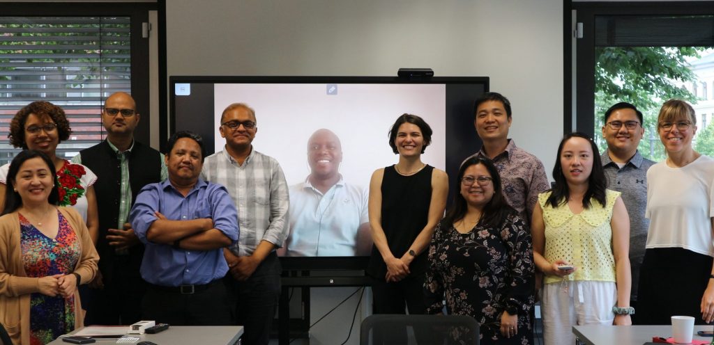 MBM Sstudents standing in front of a screen, looking at the camera.