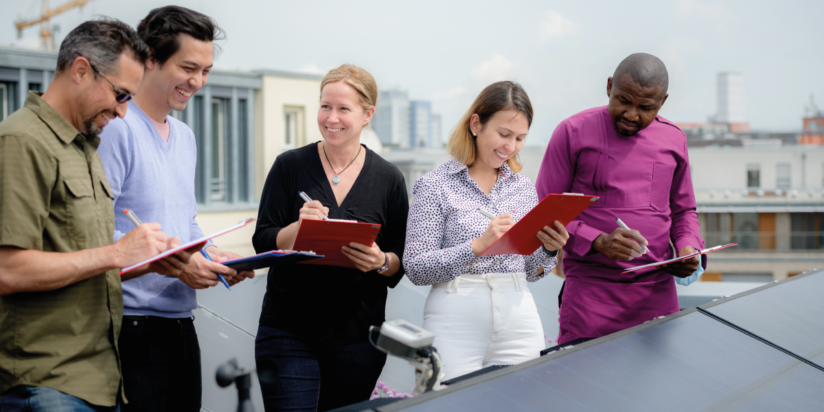 MBA Students standing behind a solar panel