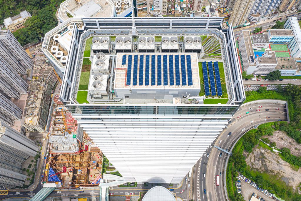 View of a building´s roof with blue solar panels and grass.