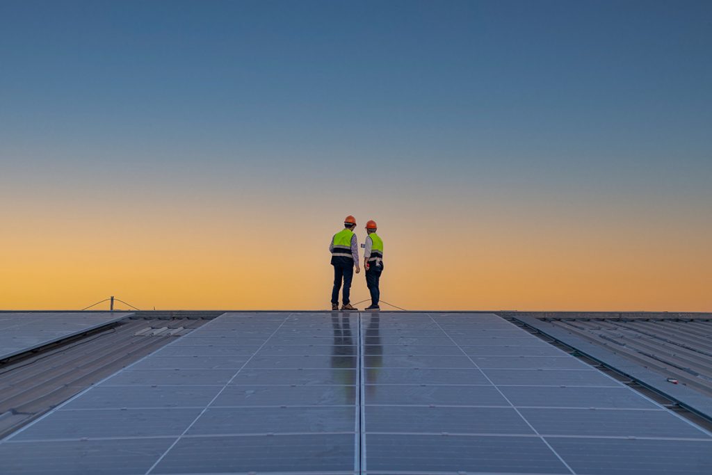 Engineers walking on roof inspect and check solar cell panel by hold equipment box and radio communication ,solar cell is smart grid ecology energy sunlight alternative power factory concept.