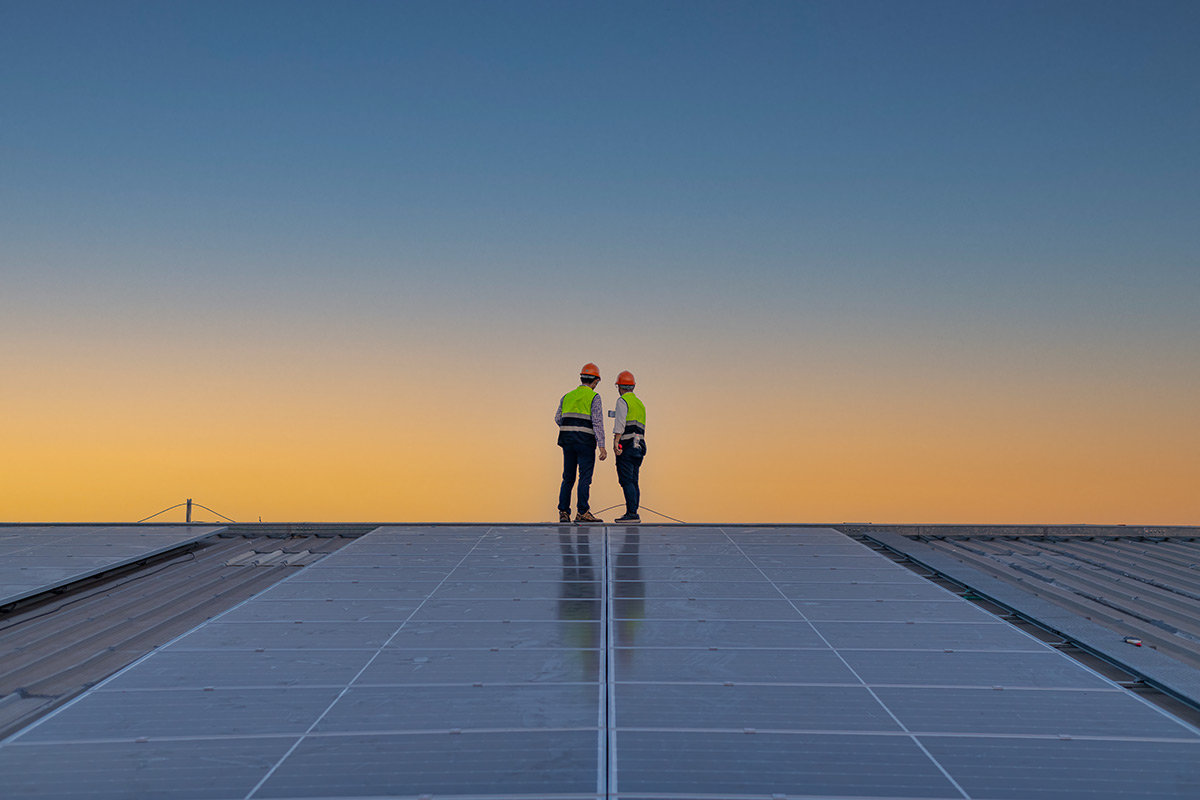 Engineers walking on roof inspect and check solar cell panel by hold equipment box and radio communication ,solar cell is smart grid ecology energy sunlight alternative power factory concept.