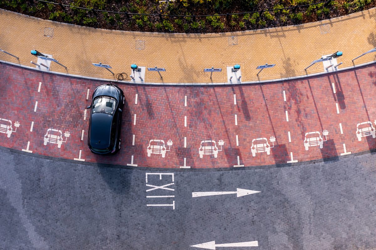 An aerial view directly above an electric vehicle charging station with electric car charging in a parking space