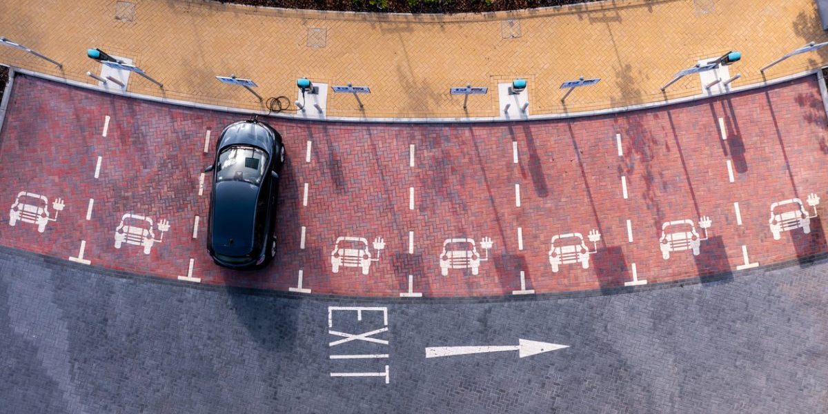 An aerial view directly above an electric vehicle charging station with electric car charging in a parking space