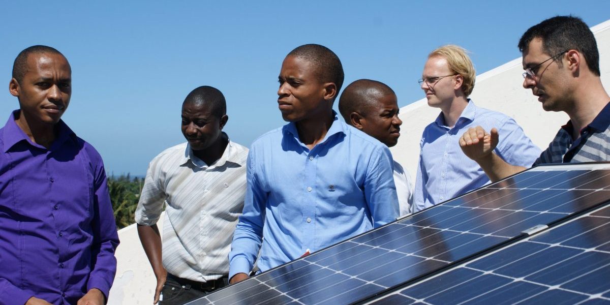 Group of trainers standing behind a solar panel