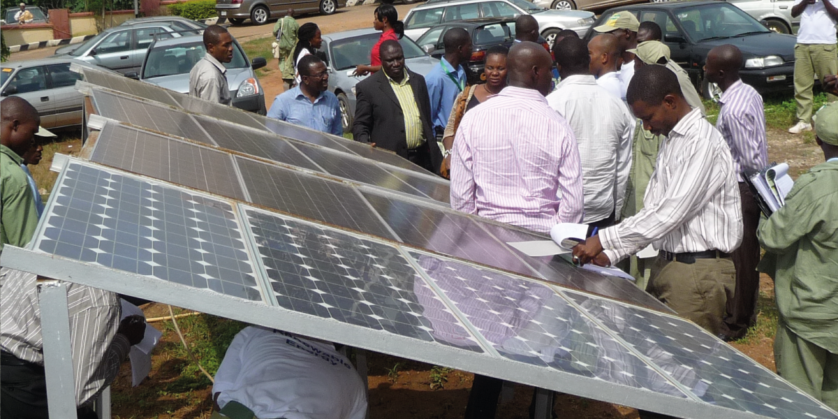 Nigerian people standing next to a solar panel